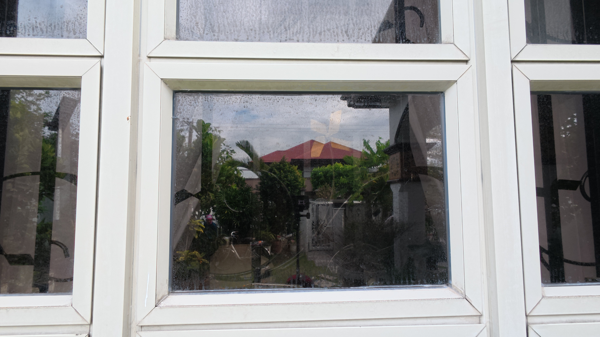Close-up of a streaky, dirty residential glass window before professional exterior softwash cleaning.