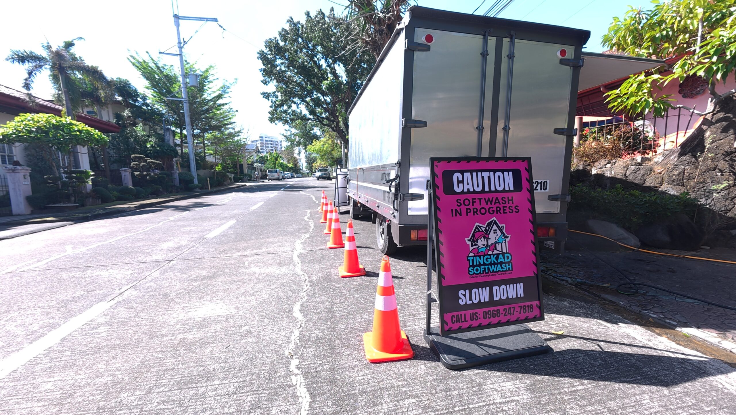 Tingkad Softwash work truck parked on a residential street with safety cones and a caution sign set up before starting a professional exterior cleaning project.