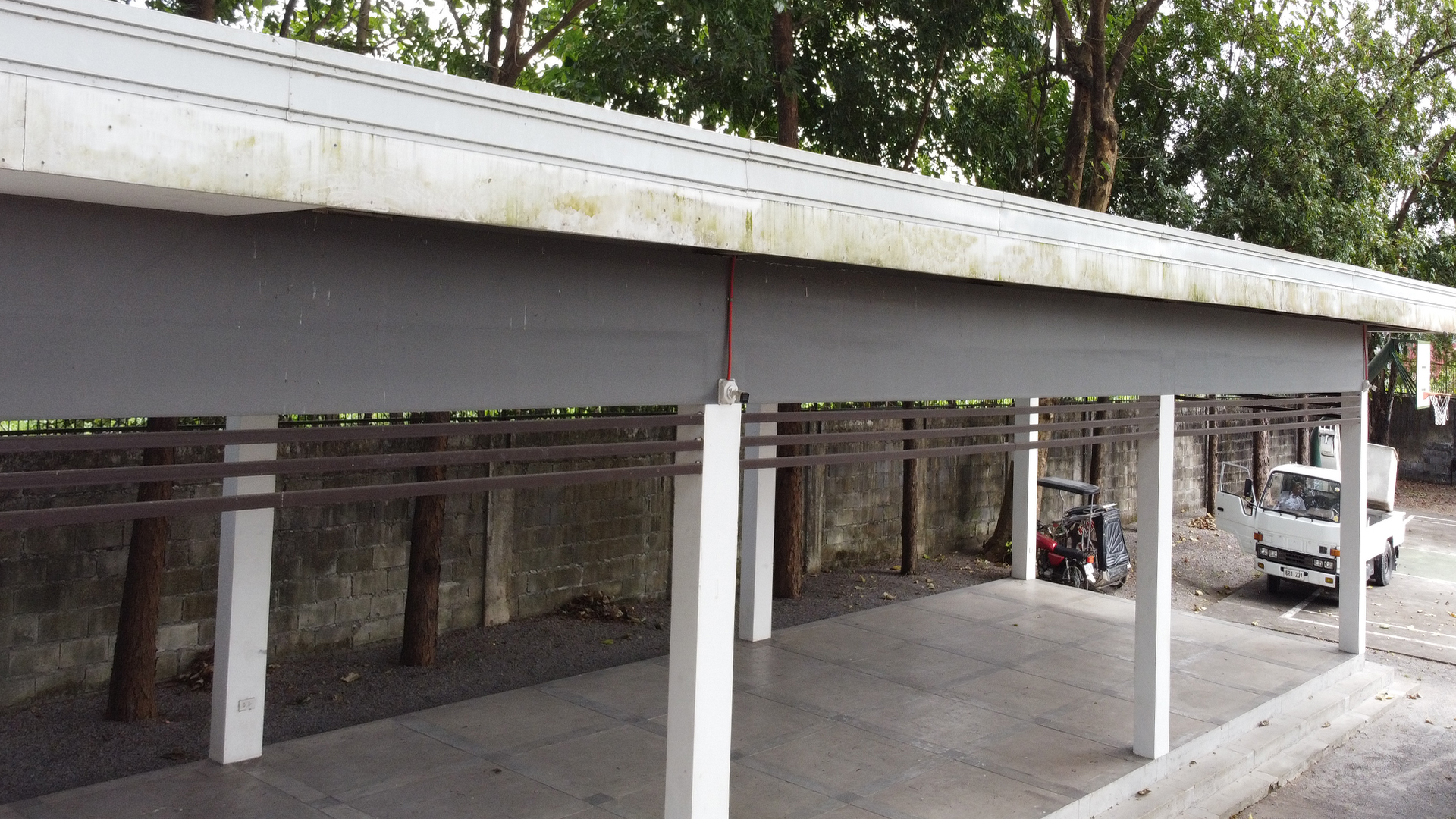 Exterior white pillars and roof fascia covered in heavy green mold and black algae buildup before cleaning.