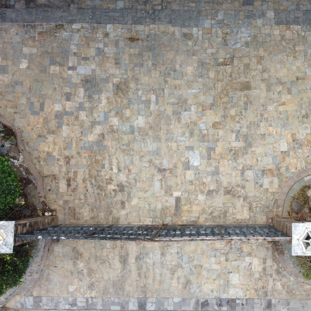 Aerial view of a large stone-tiled driveway completely cleared of algae and stains by Tingkad Softwash.