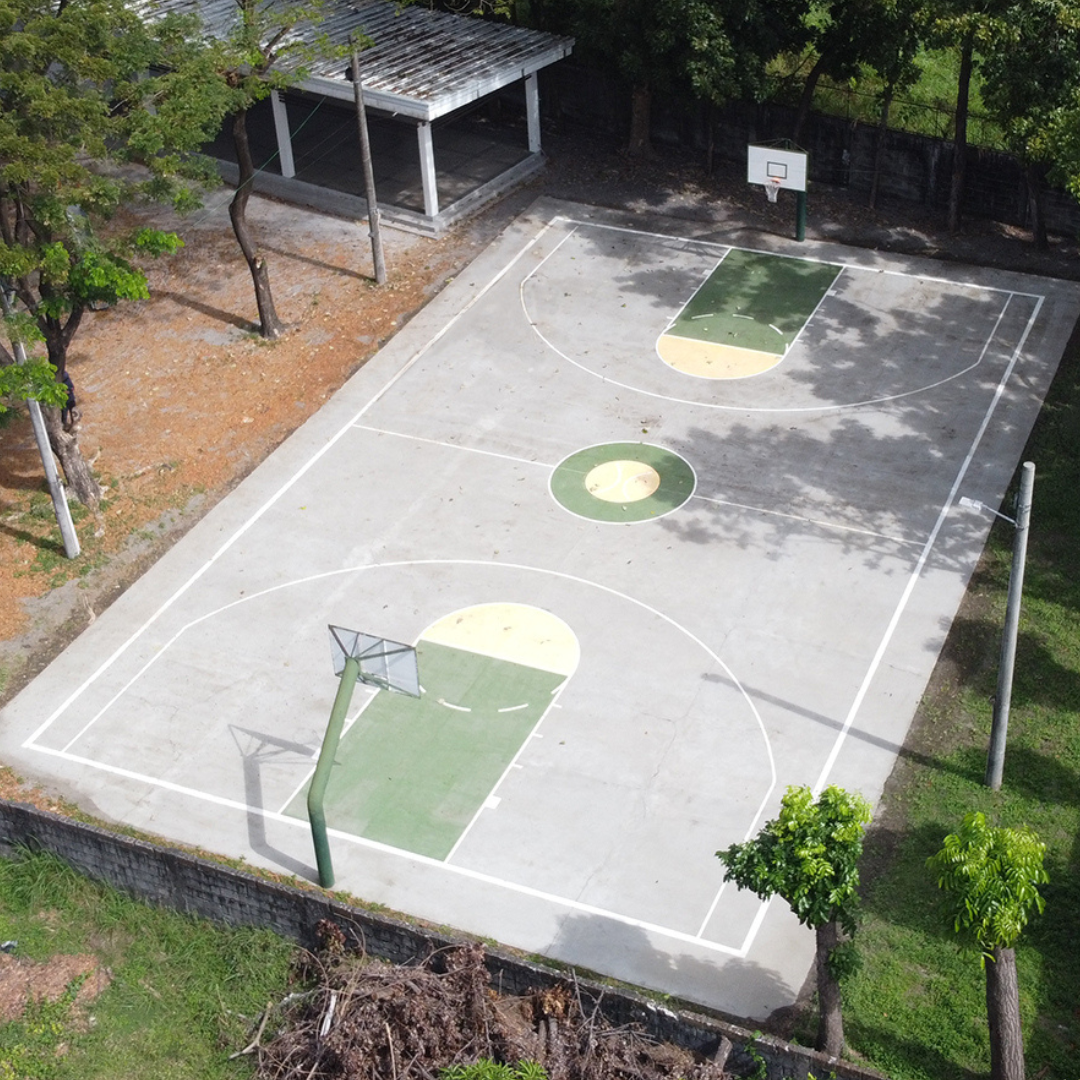 Fully restored outdoor basketball court with bright white boundary lines and clean green and yellow painted surfaces.