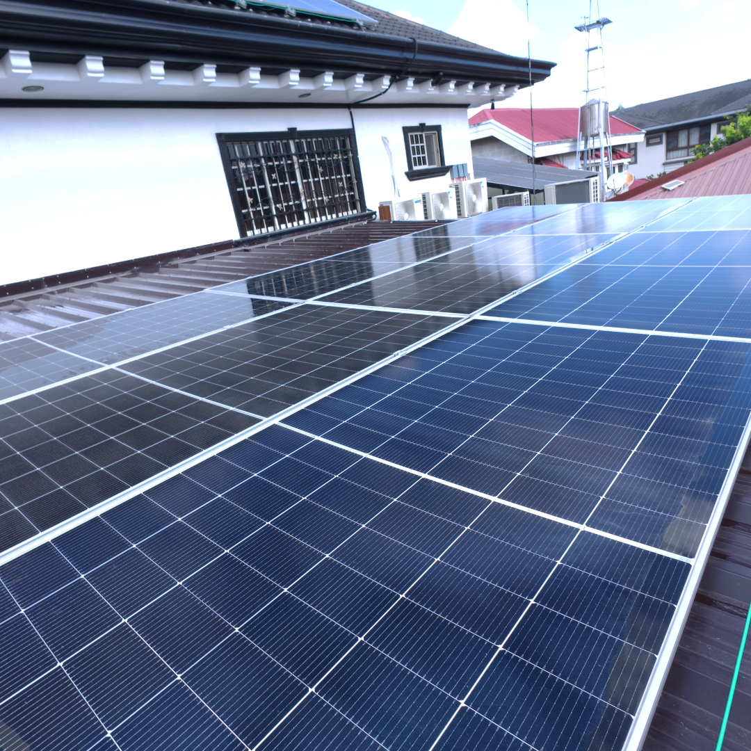 Wide-angle view of a large, clean solar panel installation on a dark corrugated metal roof.