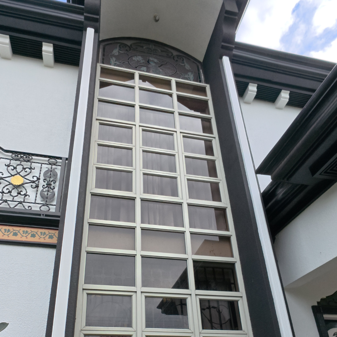 A tall, architectural multi-pane window display after professional exterior cleaning, showcasing clear glass and bright frames against a dark wall.