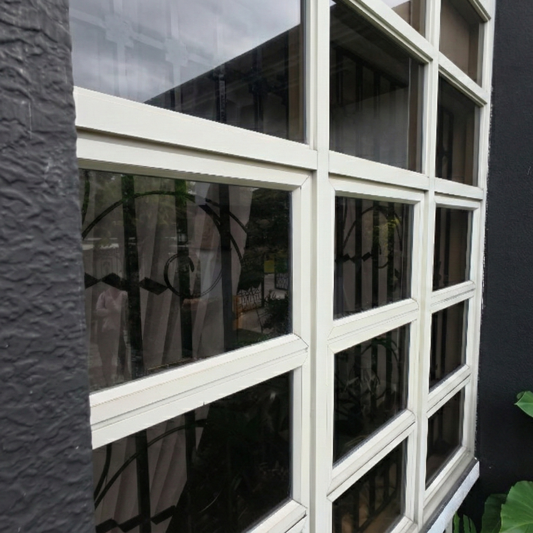 Side-profile of a perfectly clean multi-pane window, highlighting streak-free glass and restored white frames.