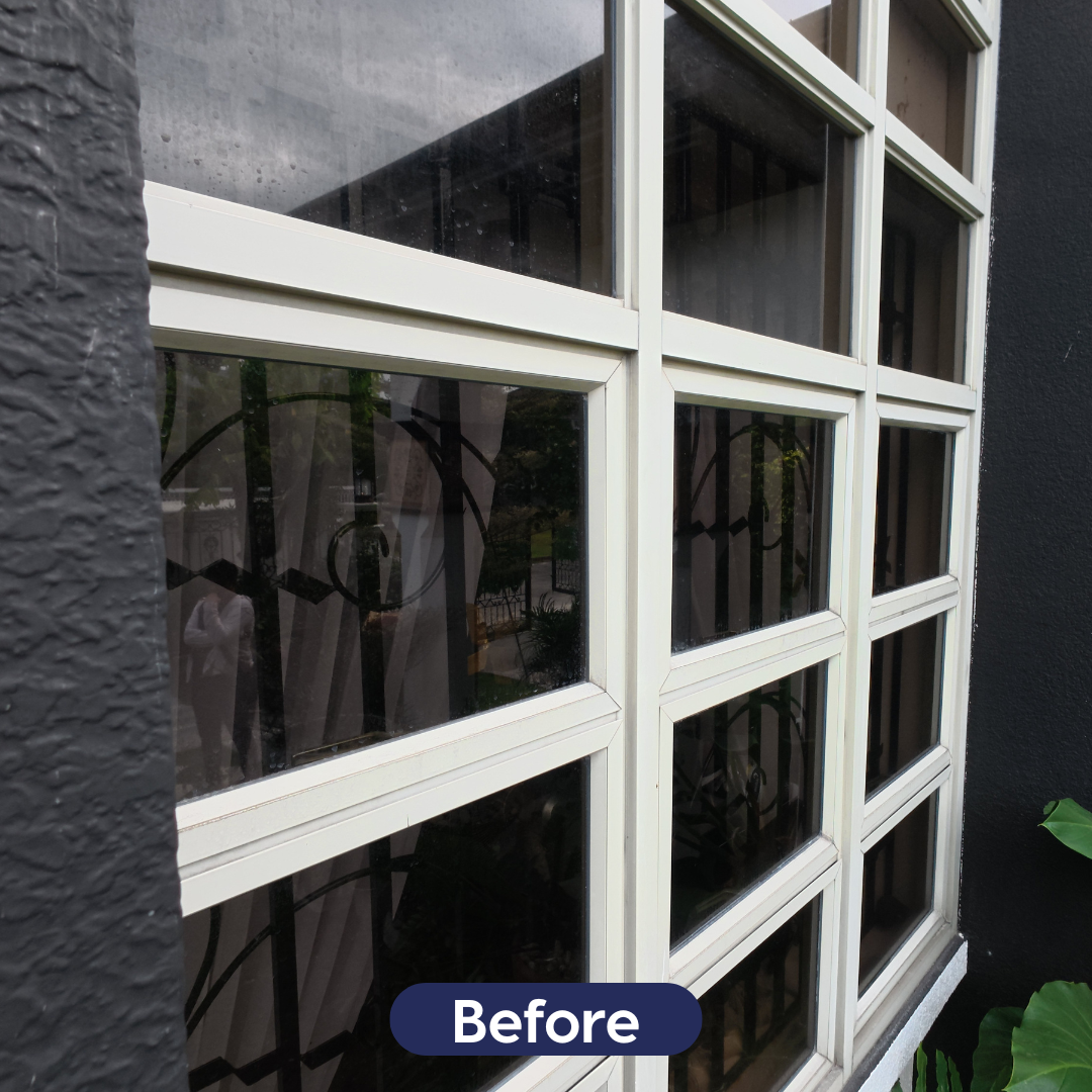 Close-up of a multi-pane window unit with significant environmental grime and dirt buildup on the glass.