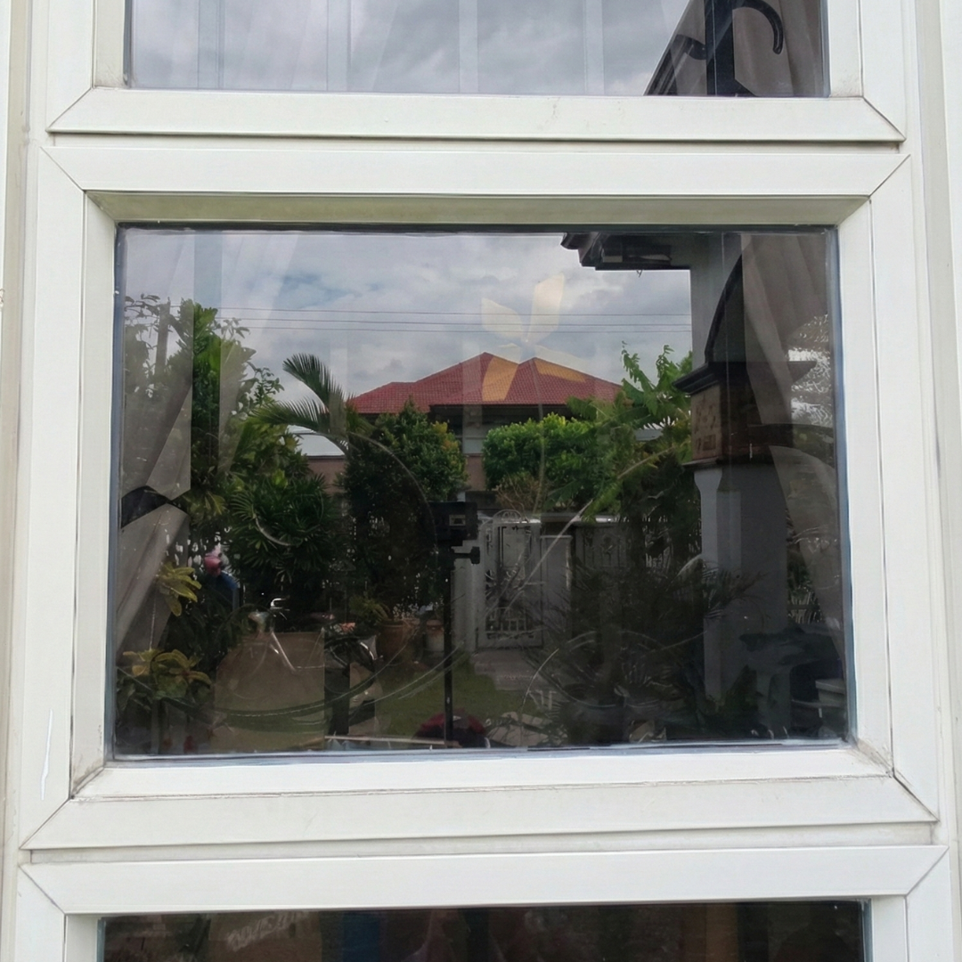 Crystal clear glass window after a deep restoration treatment by Tingkad Softwash, showing a sharp reflection of the surrounding landscape.
