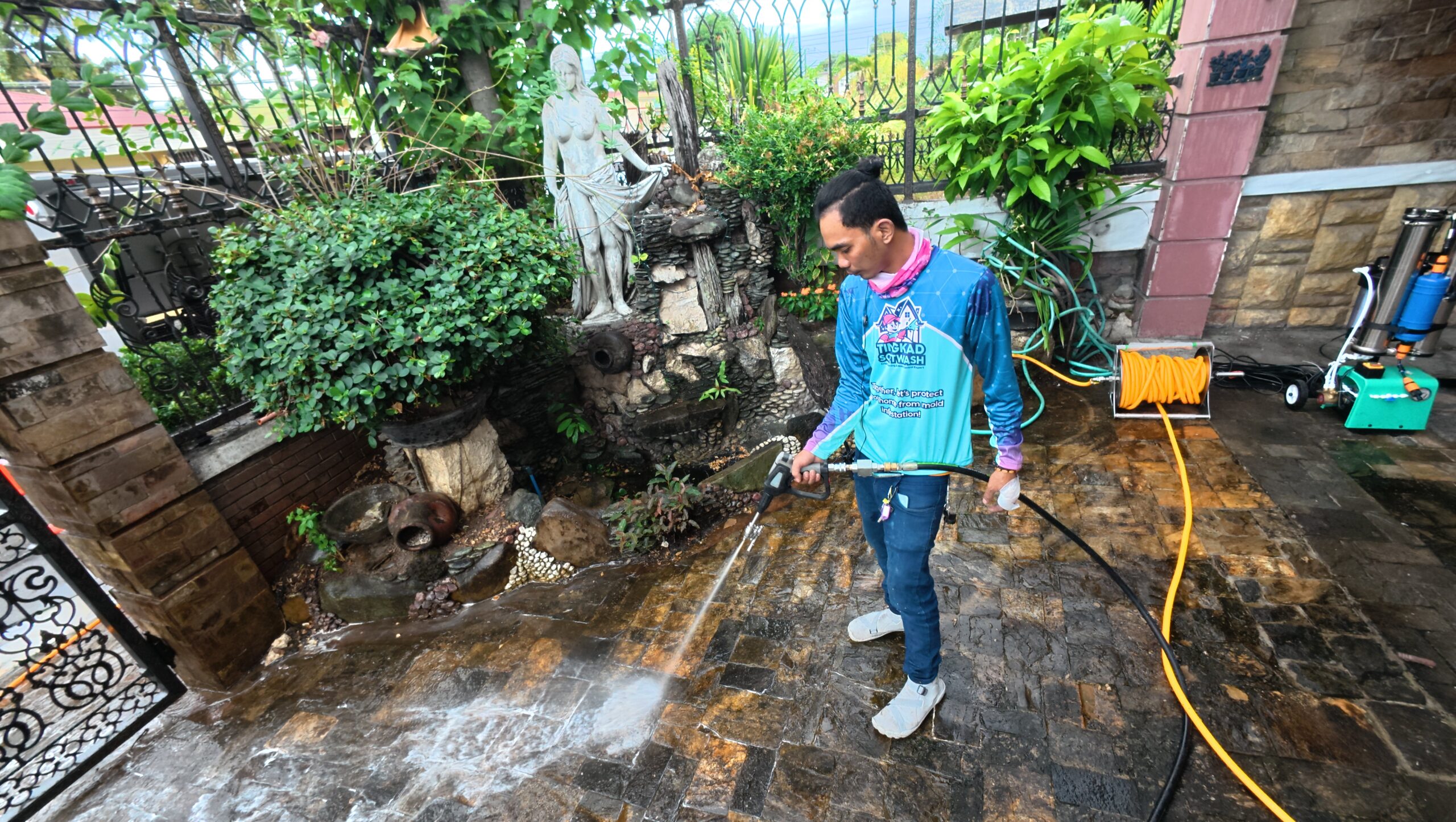 Tingkad Softwash professional gently cleaning a residential stone garden pathway using safe exterior softwashing techniques.